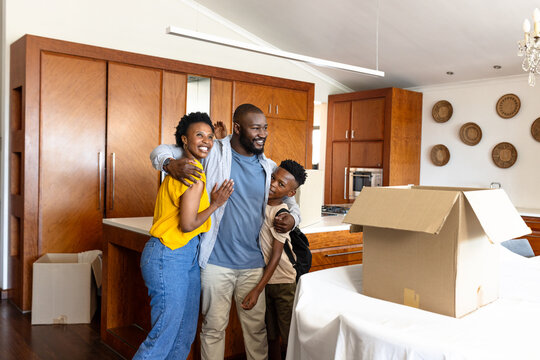 Family unpacking cardboard boxes in kitchen, smiling and enjoying new home