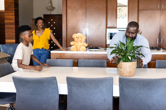 Arranging plant on dining table, African American family spending time together at home
