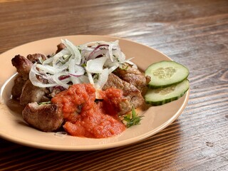 Savor the experience of Delicious Grilled Meat paired with Fresh Vegetables and flavorful Sauce. Enjoy grilled meat topped with crispy fried onions, rich tomato sauce, and crunchy cucumber slices