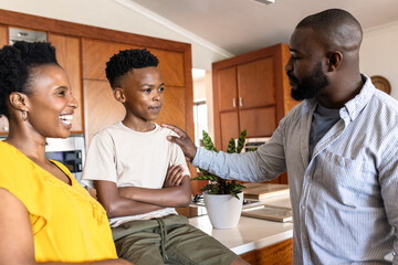 In kitchen, African American family bonding and smiling during conversation together, at home