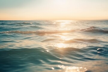 Obraz premium Sunset over calm ocean with sun reflections on waves.