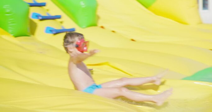 Child sliding on inflatable water slide outdoors