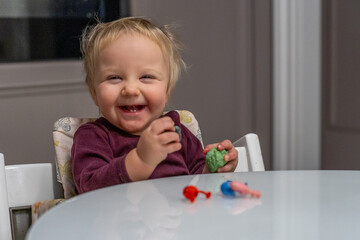 Naklejka premium Joyful Infant's Playtime: A Baby's Glee with Toy, indoor close-up, depicting childhood innocence and happiness.