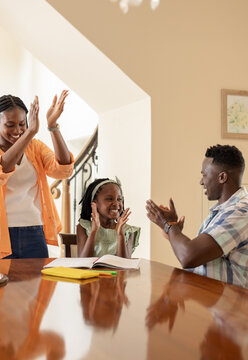 Family celebrating young girl's achievement at home, clapping and smiling together