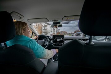 A woman adeptly driving a car through bustling urban streets filled with life and activity