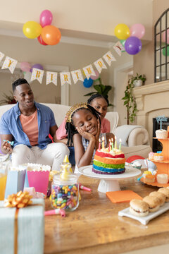 At party, Celebrating birthday at home, family gathering around cake with colorful decorations