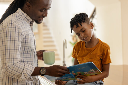 Father and son reading book together at home, enjoying quality time