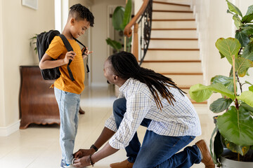 African American father tying son's shoes at home, preparing for school