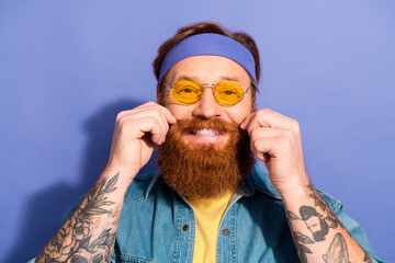 Stylish bearded man wearing a headband and yellow sunglasses smiling confidently, showcasing his...