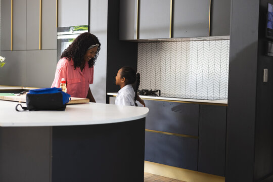 mother and daughter talking in modern kitchen before school, sharing moment, at home