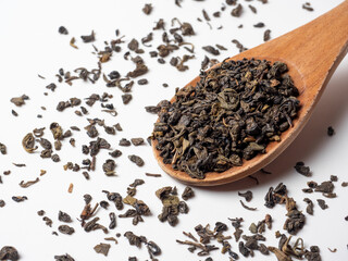 dry black tea leaves in a wooden spoon on a white background. Healthy tonic drink