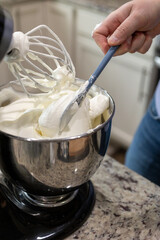 Whipped cream being mixed in a stand mixer bowl.
