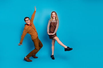 Energetic young couple posing enthusiastically against a bright blue background, showcasing retro...