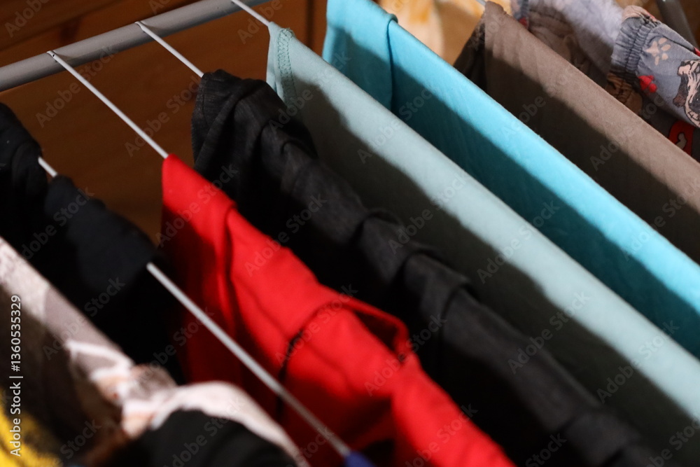 Poster a collection of variously colored shirts stacked on a shelf in a closet.