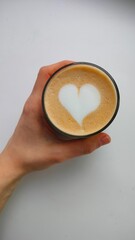 Cappuccino with heart shape. Latte art, heart-shaped decoration on coffee. Cup on coffee in hand, isolated background