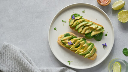 Vegan food concept. Healthy breakfast, homemade sourdough bread with avocado slices. Top view, copy space, gray textured background.          