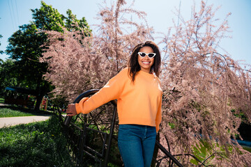 Photo of positive good mood woman dressed orange pullover dark eyewear walking outdoors urban city...