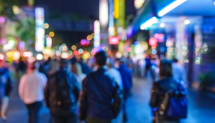 Fototapeta premium Personas variadas caminando con desenfoque de movimiento por por la noche una calle de ciudad iluminada con ambiente cálido