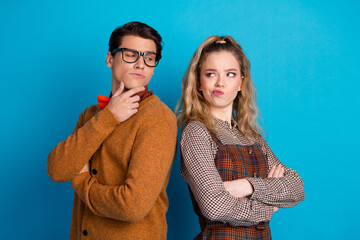Young couple standing playfully with crossed arms against a vibrant blue background