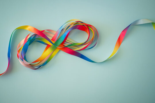 Autism acceptance month, Autism awareness day concept. Rainbow colors ribbons in shape of infinity loop on blue background. Infinity is symbol of autism disorder, adhd, neurodiversity - Powered by Adobe