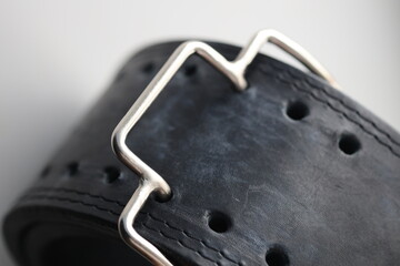 Close-up of a black leather belt with a silver buckle, suitable for use in fashion or accessories editorial.