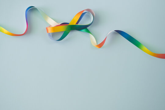 Autism acceptance month, Autism awareness day concept. Rainbow colors ribbons in shape of infinity loop on blue background. Infinity is symbol of autism disorder, adhd, neurodiversity