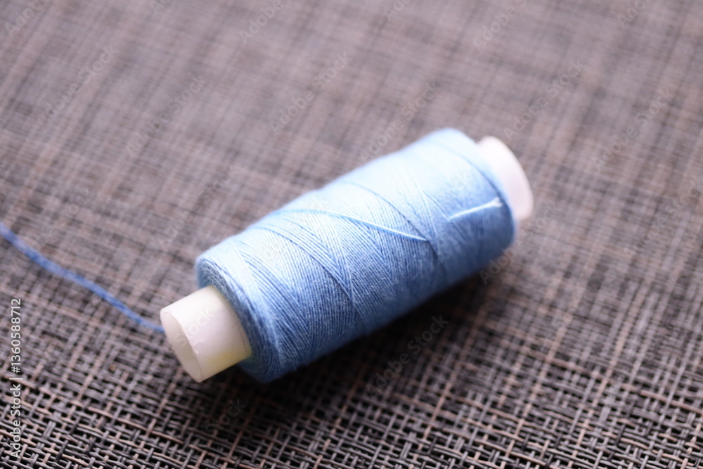 Poster A spool of thread sits on top of a table, ready for use.