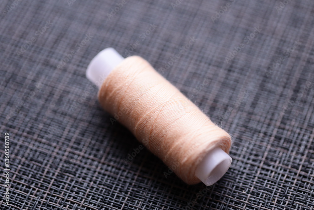 Poster A single spool of thread sits on a table, awaiting use in sewing or crafting projects.