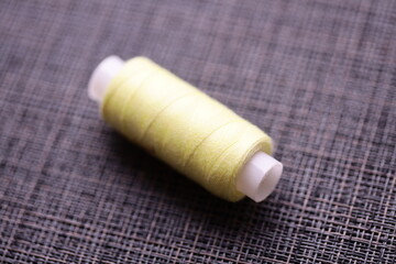 A single spool of yellow thread sits on a table, ready for use.
