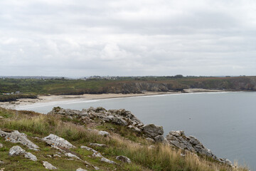 Ambiance sauvage sur la plage du Veryac’h, où les nuages soulignent le relief des falaises.