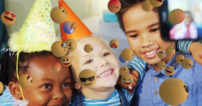 Children at birthday party smiling and taking selfie with emoji decorations