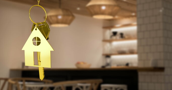 Golden house keychain hanging in modern kitchen, symbolizing new home ownership