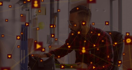 Man in office using tablet surrounded by digital interface icons and connections