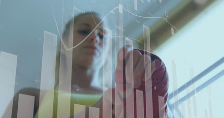 Woman in boxing gloves interacting with digital financial graphs, focused on data
