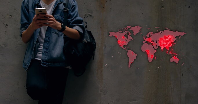 Young man checking smartphone with world map highlighting pandemic hotspots