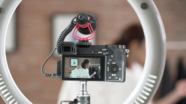 Rear view behide camera screen display woman influencer shoot vlog video review clothes prim social media or blog. Girl with apparel studio lighting for vivancy live streaming marketing recording