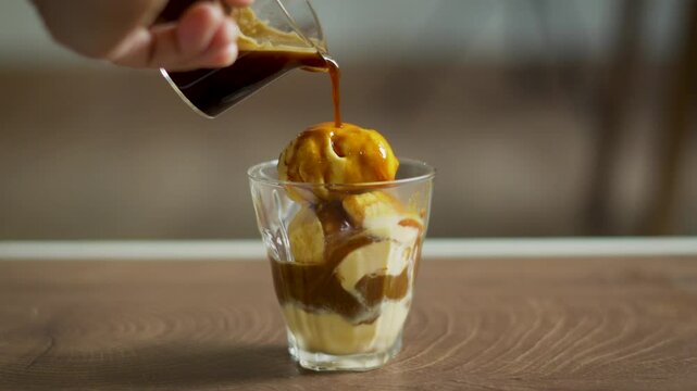 classic Italian Affogato of hand pouring espresso into vanilla ice cream, blending bitter and sweet flavors into a creamy aromatic dessert drink.