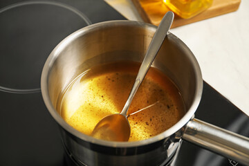 Used cooking oil and spoon in saute pan on stove, closeup