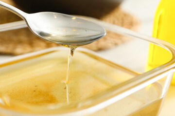 Pouring used cooking oil into glass container at white table, closeup