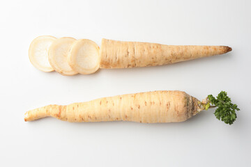 Whole and cut parsley roots on white background, flat lay