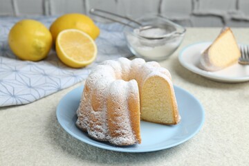 Delicious lemon cake with powdered sugar on light textured table, closeup
