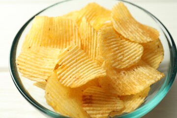 Tasty potato chips in bowl on white table, closeup