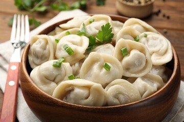 Delicious dumplings with fresh green onion and parsley served on table, closeup