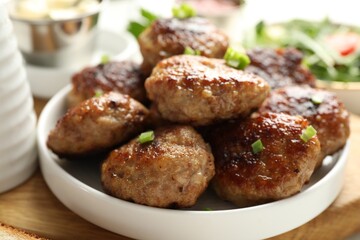 Delicious patties with green onions on table, closeup