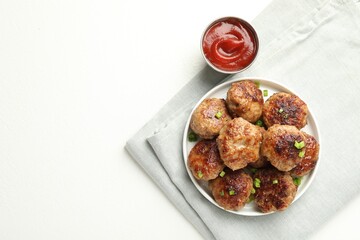 Delicious patties with green onions and ketchup on white table, top view. Space for text