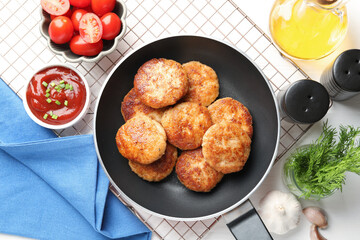 Delicious patties, spices, tomatoes and ketchup on white wooden table, flat lay