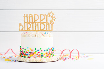 Delicious bento cake with colorful sprinkles, topper and serpentine streamer on white table. Space for text