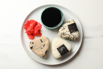 Rice balls (onigiri), soy sauce and pickled ginger on light table, top view. Traditional Japanese dish