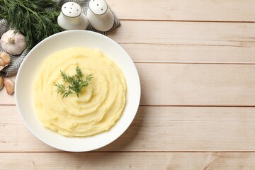 Tasty mashed potato with dill in bowl and spices on light wooden table, flat lay. Space for text