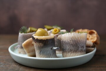 Delicious herring rolls with olives and dill on table, closeup